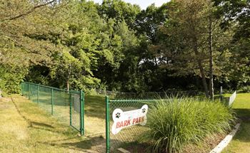 A sign for a park is on a green fence